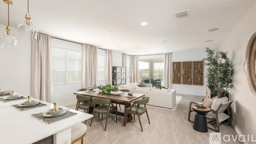 A modern dining room with a table set for two and a sofa with a cushion.