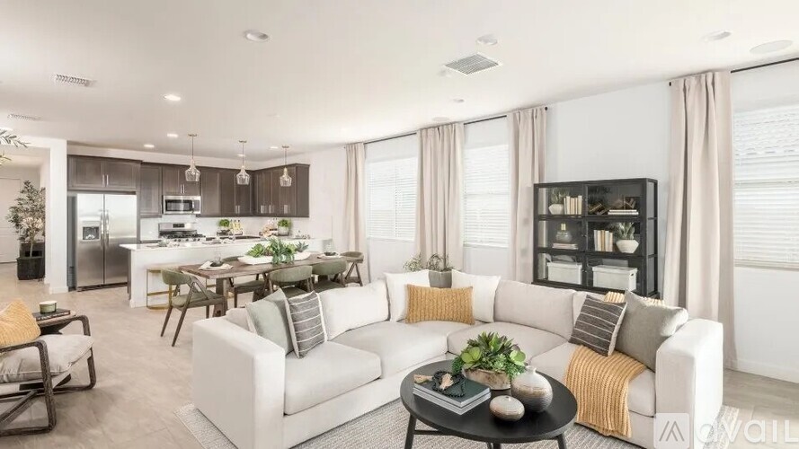 A modern living room with a white sofa, a coffee table, and a kitchen in the background.
