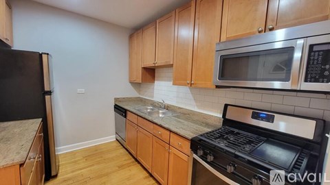 A kitchen with wooden cabinets and a black fridge.