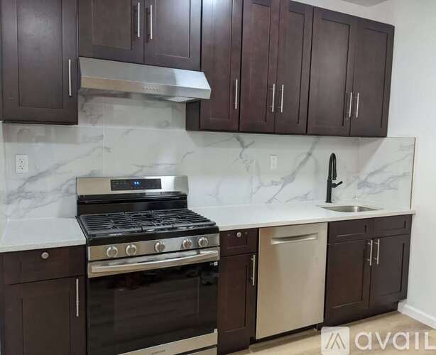A kitchen with dark brown cabinets and a white marble countertop.