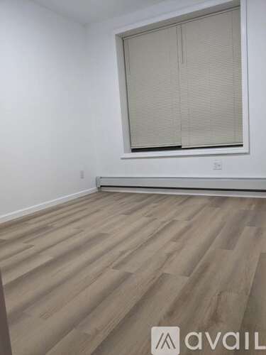 A room with a window and wooden flooring.