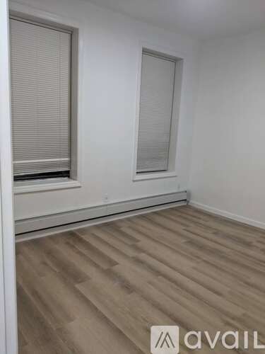 A room with wooden flooring and a window with blinds.