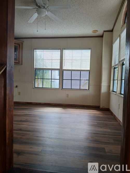 A room with a ceiling fan and wooden floors.