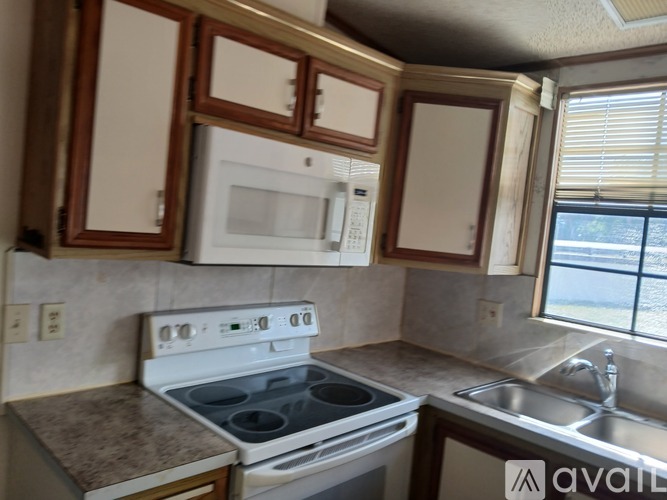 A kitchen with a white stove top oven and microwave above it.