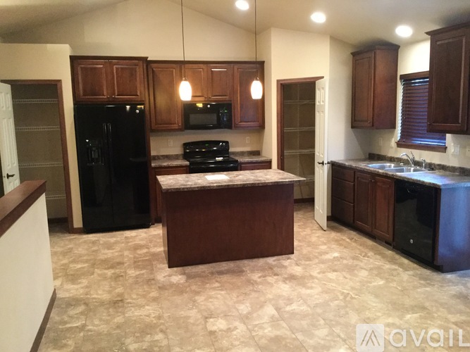 A kitchen with a black refrigerator and wooden cabinets.
