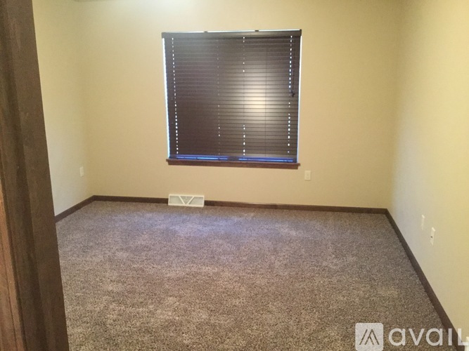 A room with a carpeted floor and a window with blinds.