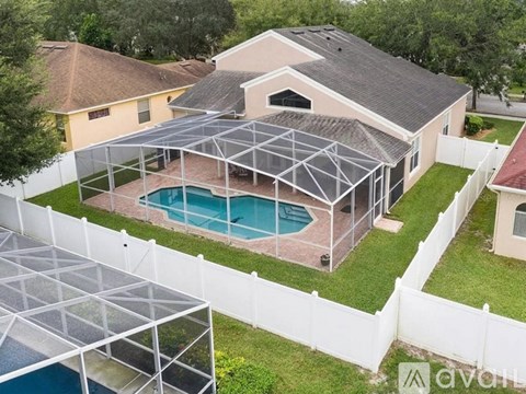 A house with a pool and a sunroom attached to it.