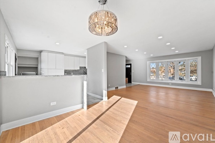 A spacious room with a wooden floor and a chandelier hanging from the ceiling.