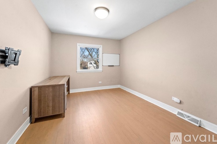 A room with a wooden cabinet and a window with a view of a building outside.