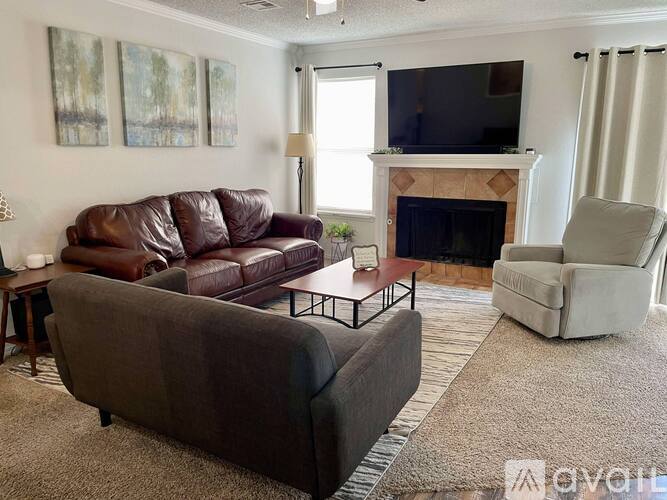 A living room with a brown leather couch, a grey couch, a fireplace, and a television.
