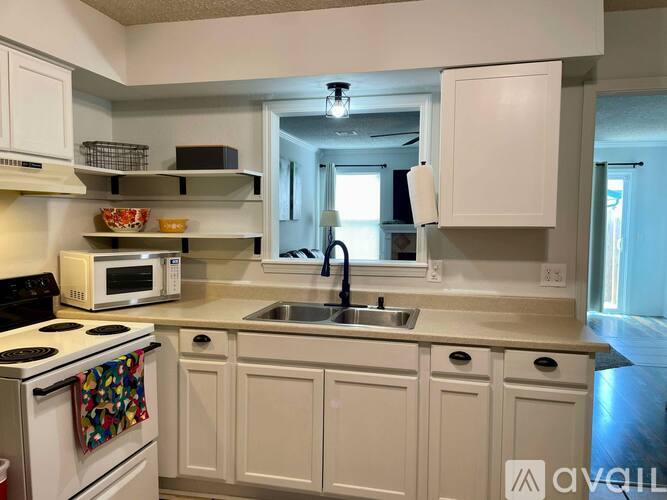A kitchen with white cabinets and a white stove top oven.