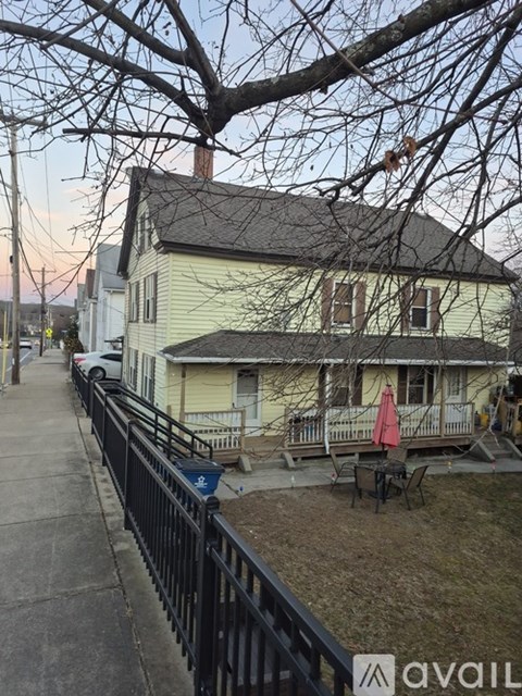 A house with a fence and a tree in front of it.