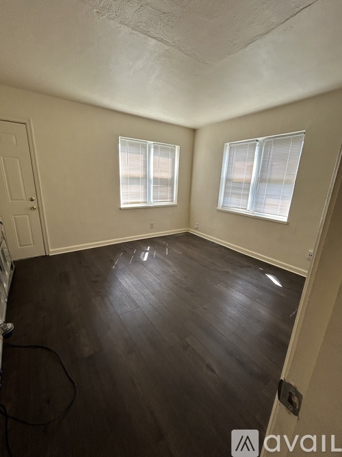 A room with wooden floors and two windows.