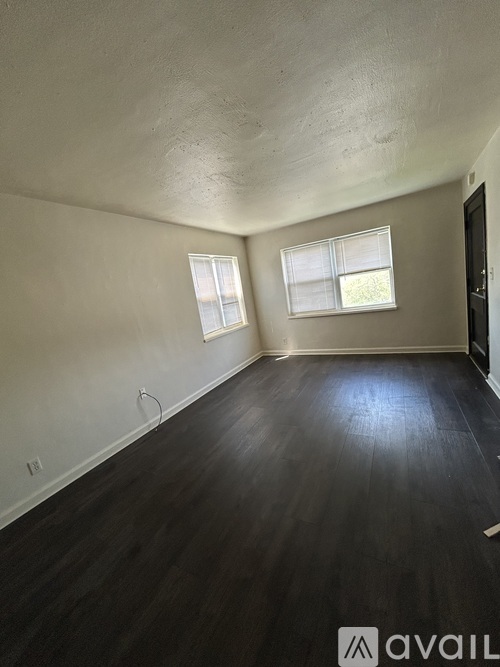 A room with wooden floors and two windows.
