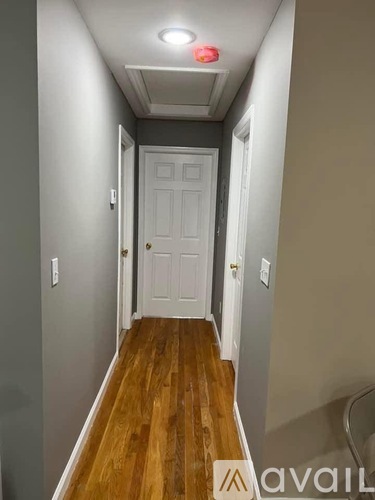 A hallway with a white door and wooden floor.