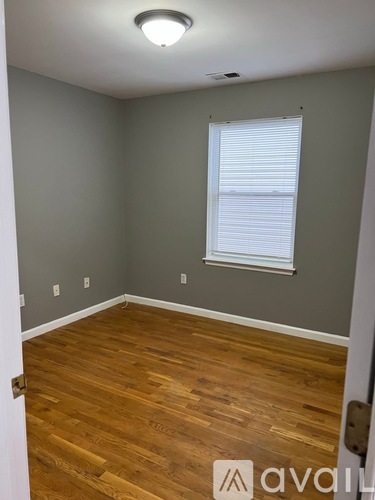 A room with wooden flooring and a window with blinds.