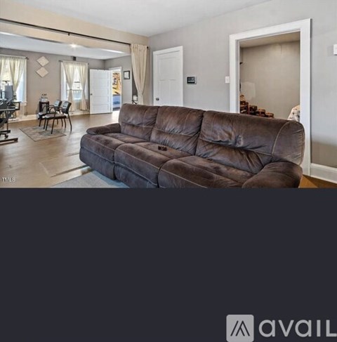 A brown sofa in a living room with a dining area in the background.