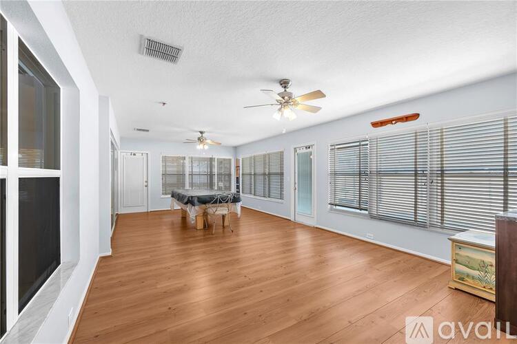 A spacious room with wooden floors and a ceiling fan.