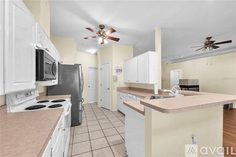 A kitchen with white cabinets and a pink countertop.