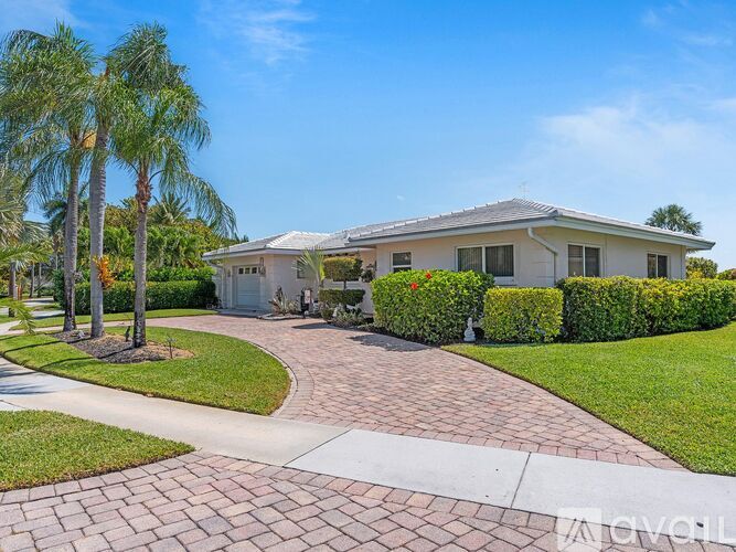 A house with a driveway and palm trees in front.