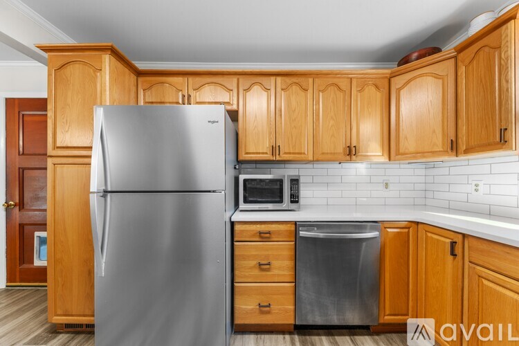 A kitchen with wooden cabinets and a stainless steel refrigerator.