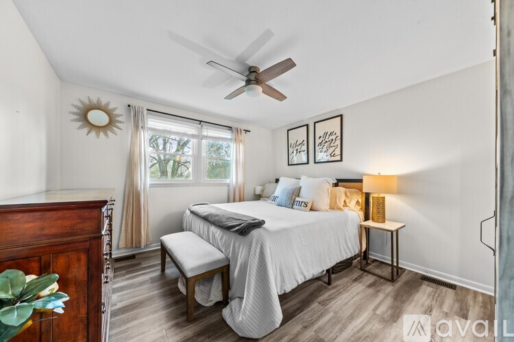 A bedroom with a bed, a bench, and a ceiling fan.