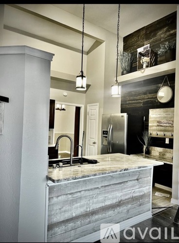 A kitchen with a marble countertop and pendant lights.
