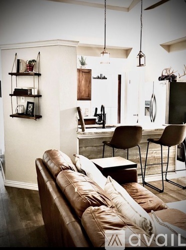 A living room with a brown leather couch and a white wall.