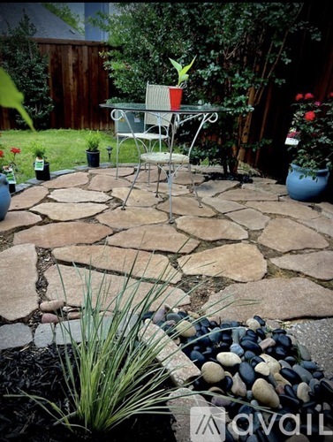 A patio with a table and chairs surrounded by a stone wall.