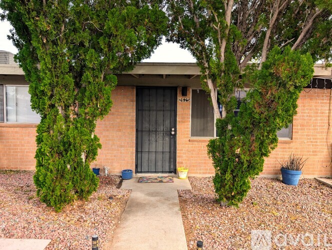 A house with a black door is surrounded by trees and bushes.