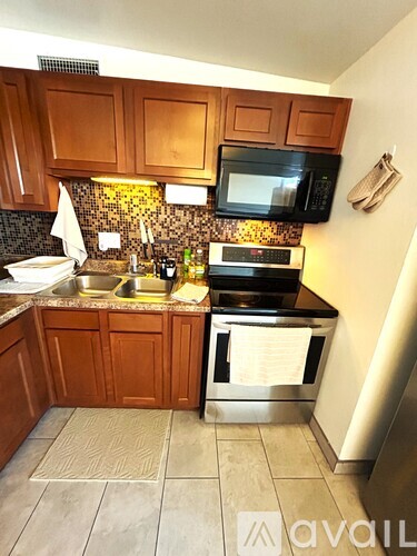 A kitchen with wooden cabinets and a black microwave above the stove.