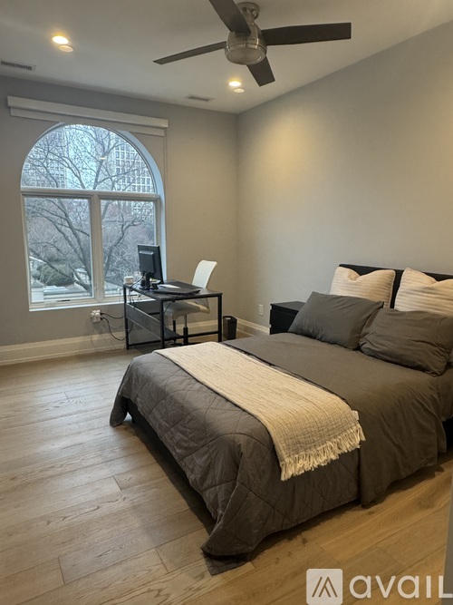 A bedroom with a large bed and a ceiling fan.