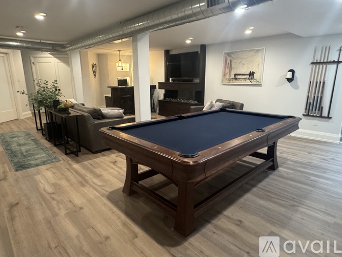 A pool table in a room with a plant and a couch.