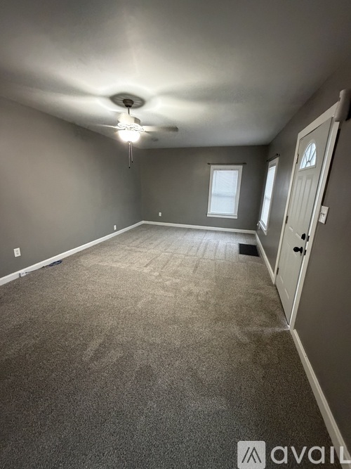 A room with a carpeted floor and a ceiling fan.