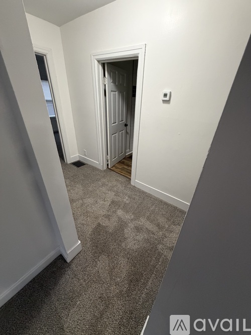 A hallway with a carpeted floor and a door at the end.