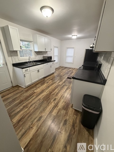 A kitchen with white cabinets and a black countertop.