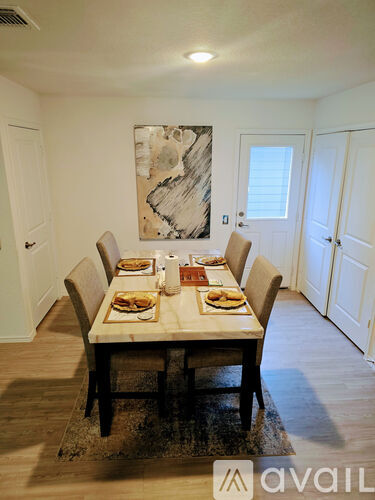 A dining room with a table set for a meal and a painting on the wall.