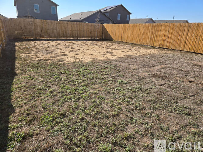 A backyard with a wooden fence and a grassy area.