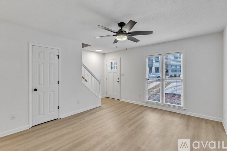 A spacious room with a ceiling fan and a view of the city through the window.