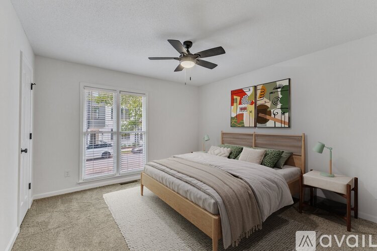 A bedroom with a bed, a ceiling fan, and a painting on the wall.