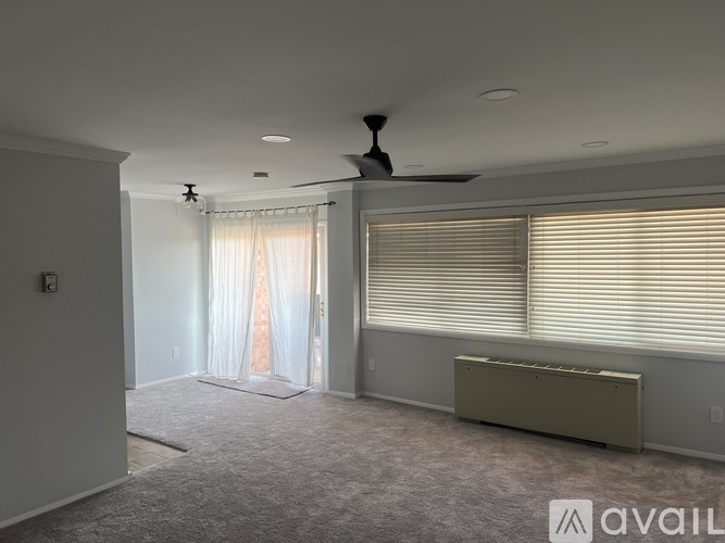 A spacious room with a ceiling fan and a window with blinds.