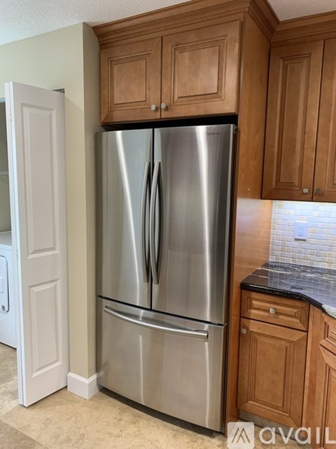 A stainless steel refrigerator in a kitchen with wooden cabinets.