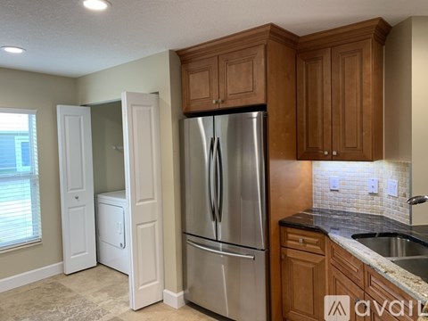 A kitchen with a refrigerator, sink, and cabinets.