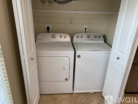 Two white front loading washing machines in a small laundry room.