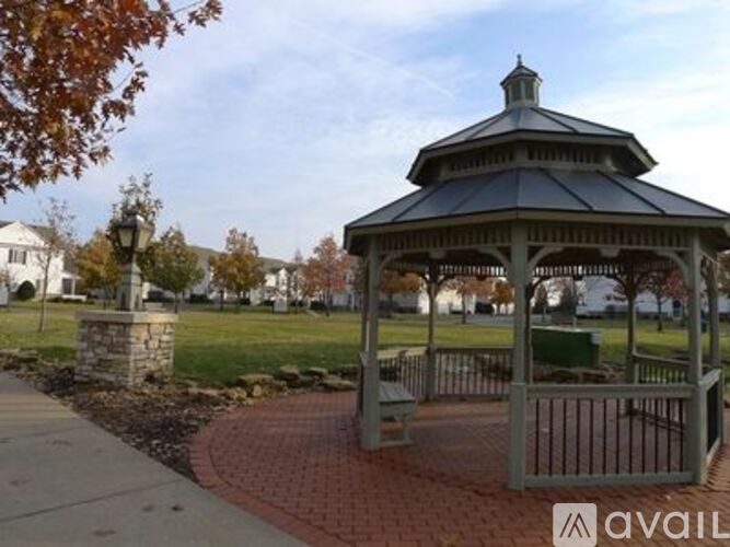 A gazebo is surrounded by a brick walkway and a metal fence.