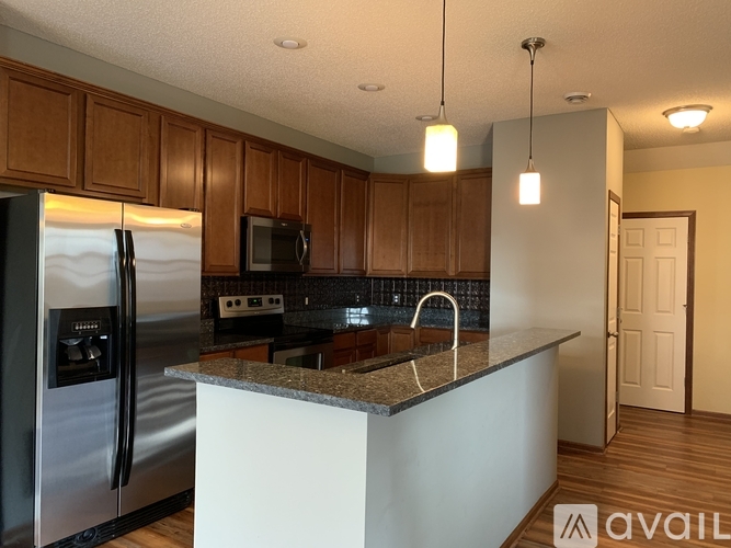 A kitchen with wooden cabinets and a stainless steel refrigerator.