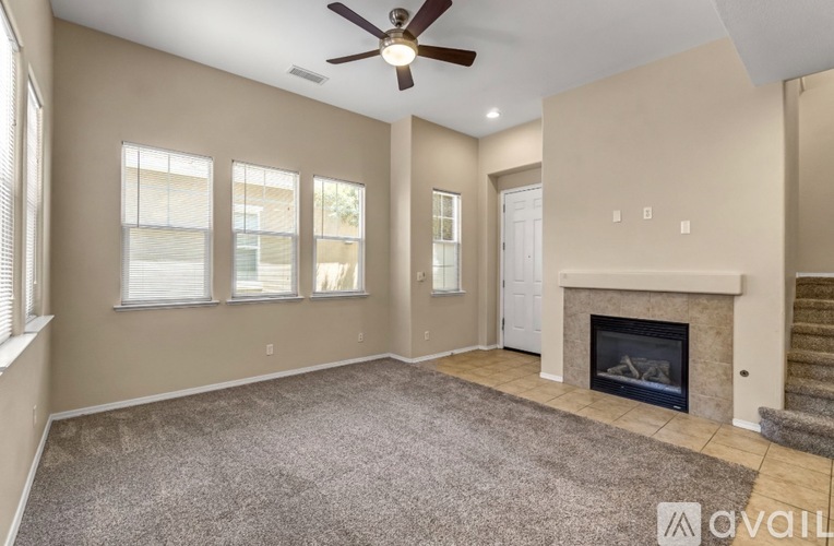 A spacious living room with a fireplace and a staircase.
