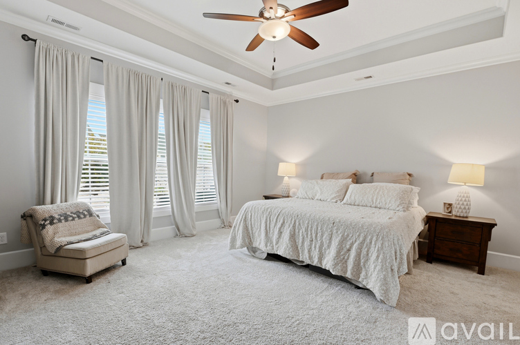 A bedroom with a large bed, a chair, and a ceiling fan.