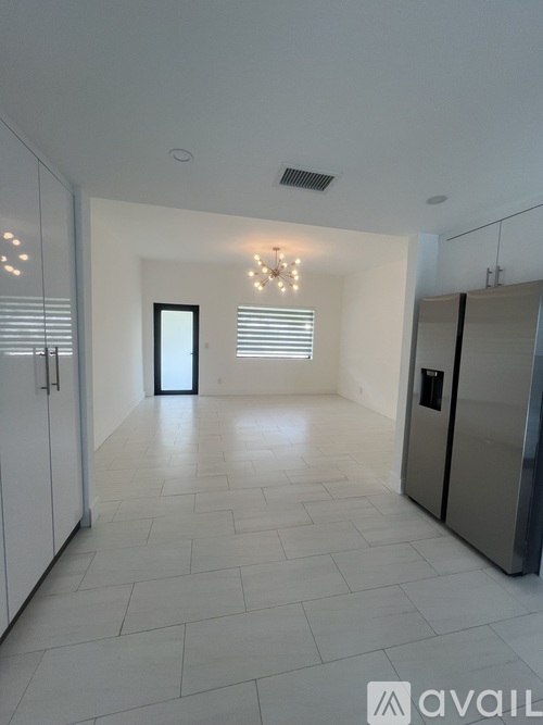 A spacious kitchen with white cabinets and a tiled floor.