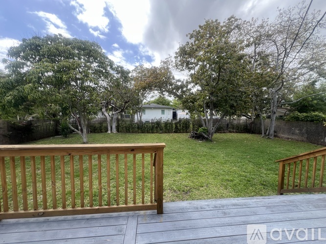 A wooden deck overlooks a green lawn and trees.